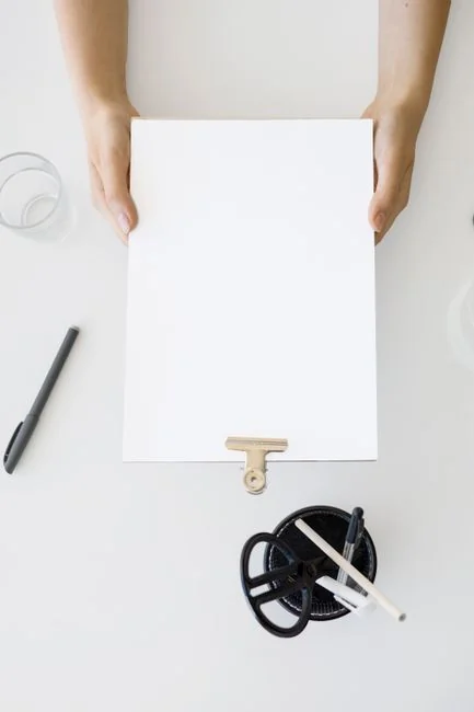 A neat workspace featuring a sketchpad with wireframes, a smartphone, and a keyboard on a wooden desk.